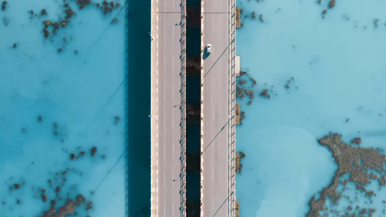 A car driving on a bridge from an aerial view